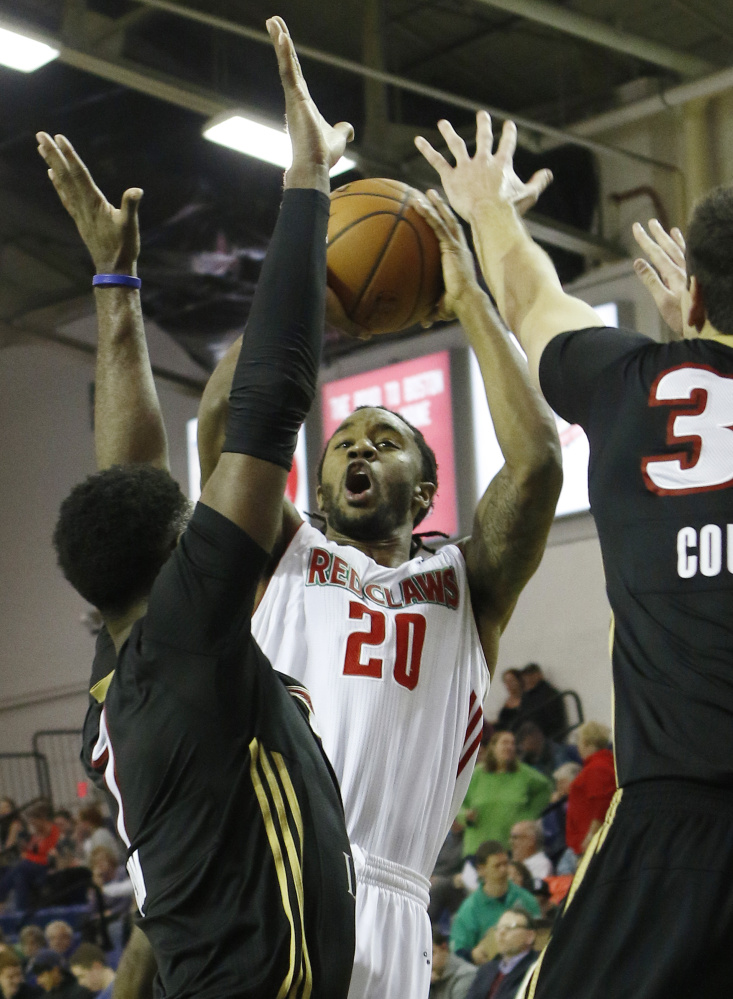 Maine’s Levi Randolph, center, takes a shot while being defended by Erie’s Melvin Ejim, left, and Daniel Coursey during the Red Claws’ 110-97 win Sunday.