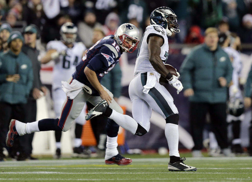 Malcolm Jenkins of the Eagles runs past Patriots quarterback Tom Brady on his way to a 99-yard interception return for a touchdown in the third quarter Sunday at Gillette Stadium. Philadelphia overcame an early 14-0 deficit and handed New England its second straight loss, 35-28.