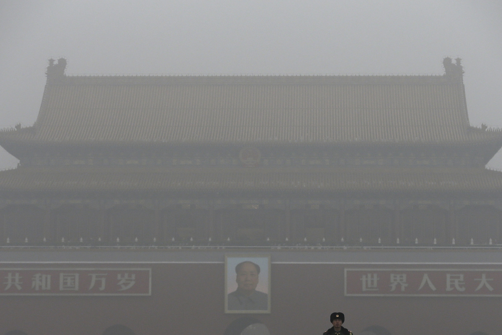 A paramilitary police officer stands guard near Tiananmen Gate shrouded with heavy pollution and fog in Beijing, China on Tuesday, Dec. 1, 2015. Schools in the capital kept students indoors and parents brought their kids to hospitals with breathing ailments Tuesday as Beijing grappled with extremely severe air pollution for the fifth straight day.