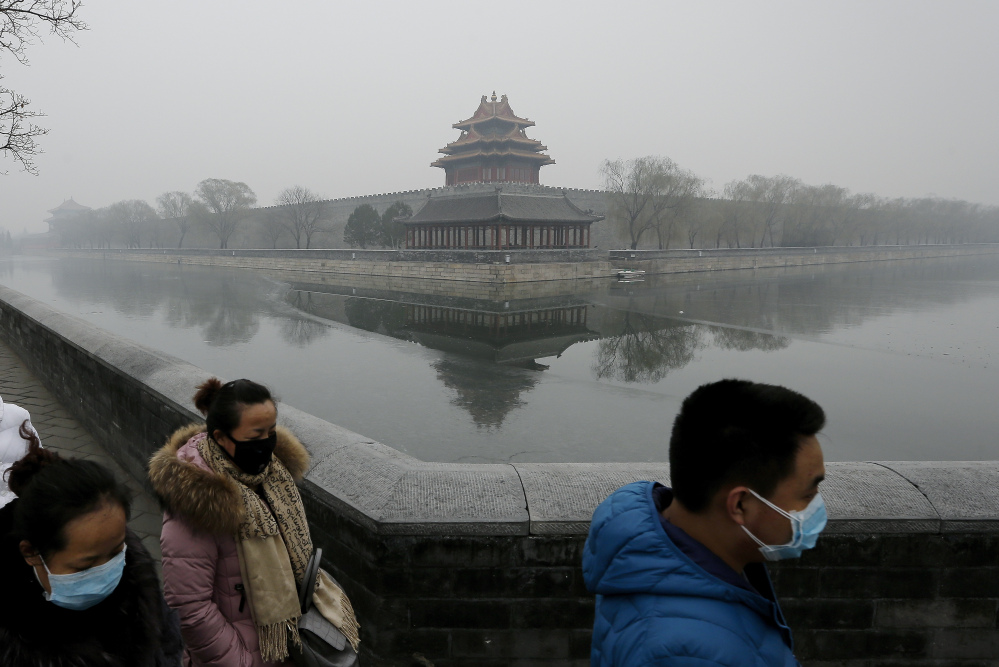 People wearing masks walk past the Turret of the Forbidden City on a heavily polluted day in Beijing Tuesday.