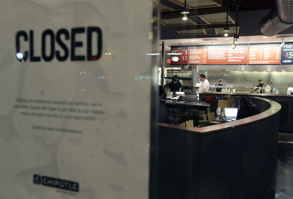 People stand inside a closed Chipotle restaurant on Monday, in the Cleveland Circle neighborhood of Boston.