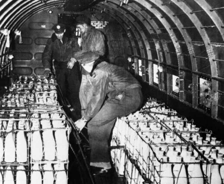 U.S. Air Force personnel strap bottles of Danish milk inside a plane at Frankfurt, Germany, on April 2, 1948, before flying to Berlin past the Soviet road blockade. A reader wonders why we aren’t similarly doing all we can to help refugees today.