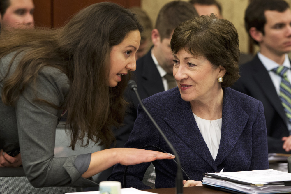 A staffer talks with Sen. Susan Collins, R-Maine, right, last month. On Wednesday, Collins and other senators condemned high drug prices.