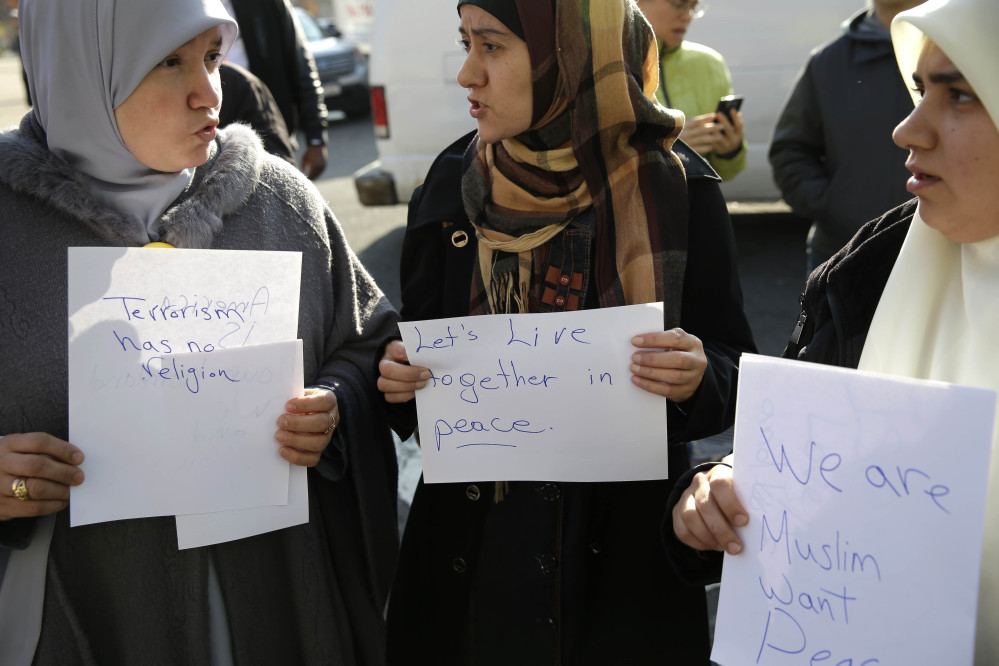 Amina Ismail, left, Fatima Amaziane, center, and Dalia Abdallah hold signs during a news conference in the Queens borough of New York on Thursday to express opposition to hate crimes and rhetoric, particularly in light of a recent attack in the neighborhood that police are investigating as a hate crime.