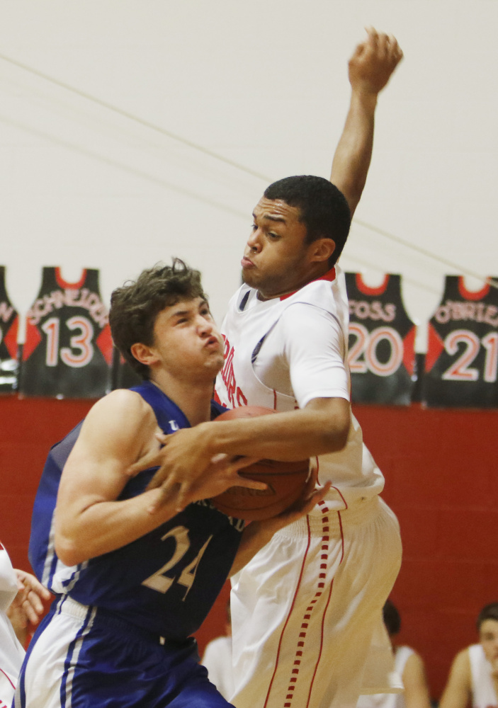 Evan Christensen of Old Orchard Beach is blocked by Deandre Woods of Wells during Thursday night’s game. Wells won the game, 38-35. Jill Brady/Staff Photographer