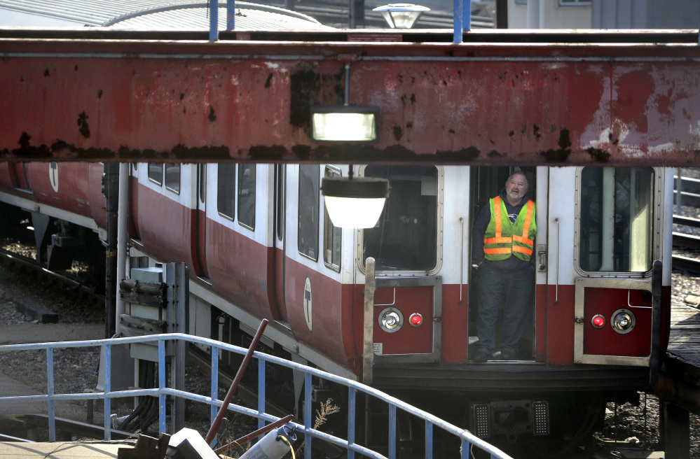 A worker stands at an entrance to a six-car train in Boston that earlier left a suburban transit station without a driver. The train went through four stations before being stopped.