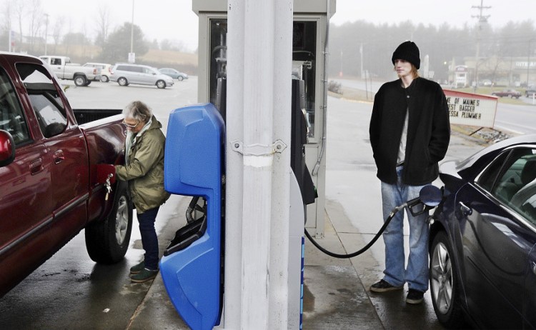 Jane Brown, left, from Standish and Aaron LeConte of Buxton fill their tanks with gas for $2 a gallon at the Sunoco gas station in Buxton. “I was a little boy the last time gas was this low,” LeConte said.