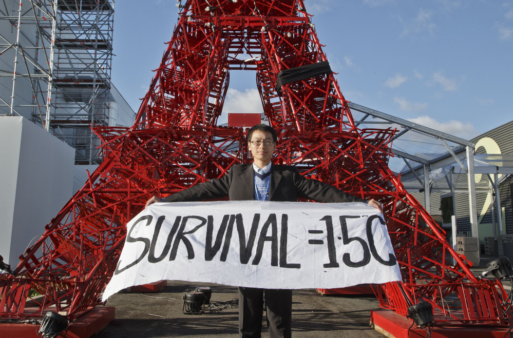 An NGO representative displays a banner in front of a reproduction of the Eiffel Tower in Paris amid a push by smaller countries this month to make the official target for global warming a threshold of 1.5 degrees Celsius. Did the conference really accomplish anything?