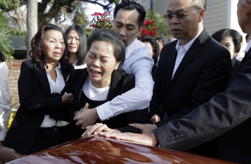 Trung Do embraces his mother Van Thanh Nguyen, center, who weeps over daugther Tin Nguyen’s coffin during Friday services in Westminster, Calif.