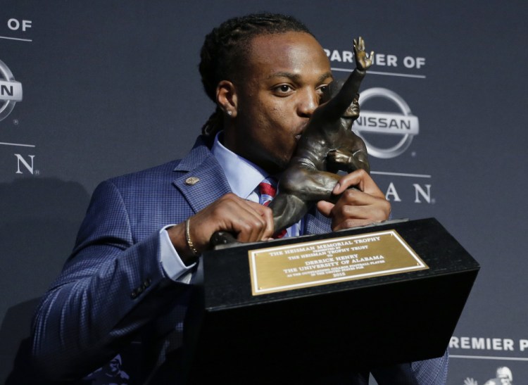 Alabama’s Derrick Henry kisses the Heisman Trophy while posing for photos after winning the award as the country’s top college football player Saturday in New York.
