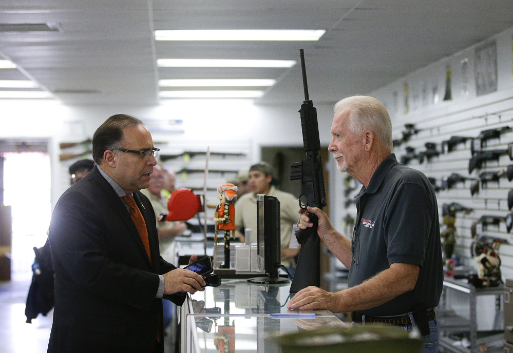 Sales associate Mike Conway, right, shows Paul Angulo a semiautomatic rifle at Bullseye Sport gun shop in Riverside, Calif.