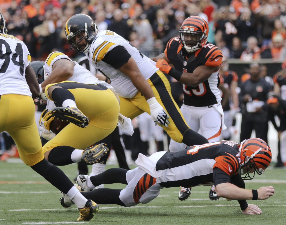 Steelers defensive end Stephon Tuitt gets tripped up by Bengals quarterback Andy Dalton after an interception Sunday. Dalton broke the thumb on his throwing hand.