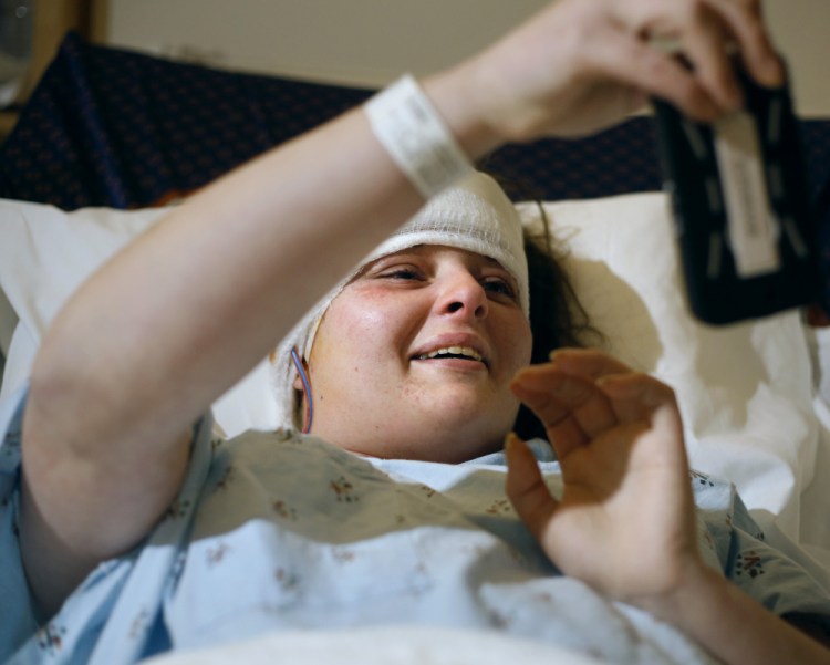 Crystal Petersen looks at family photos on her mother’s smartphone at Central Maine Medical Center in Lewiston on Tuesday after having skull surgery. She was critically injured in August in a car crash that killed her 4-year-old son. The driver of the car, Michael Minson, has been charged with manslaughter and is being held on $20,000 bail. 
Derek Davis/Staff Photographer