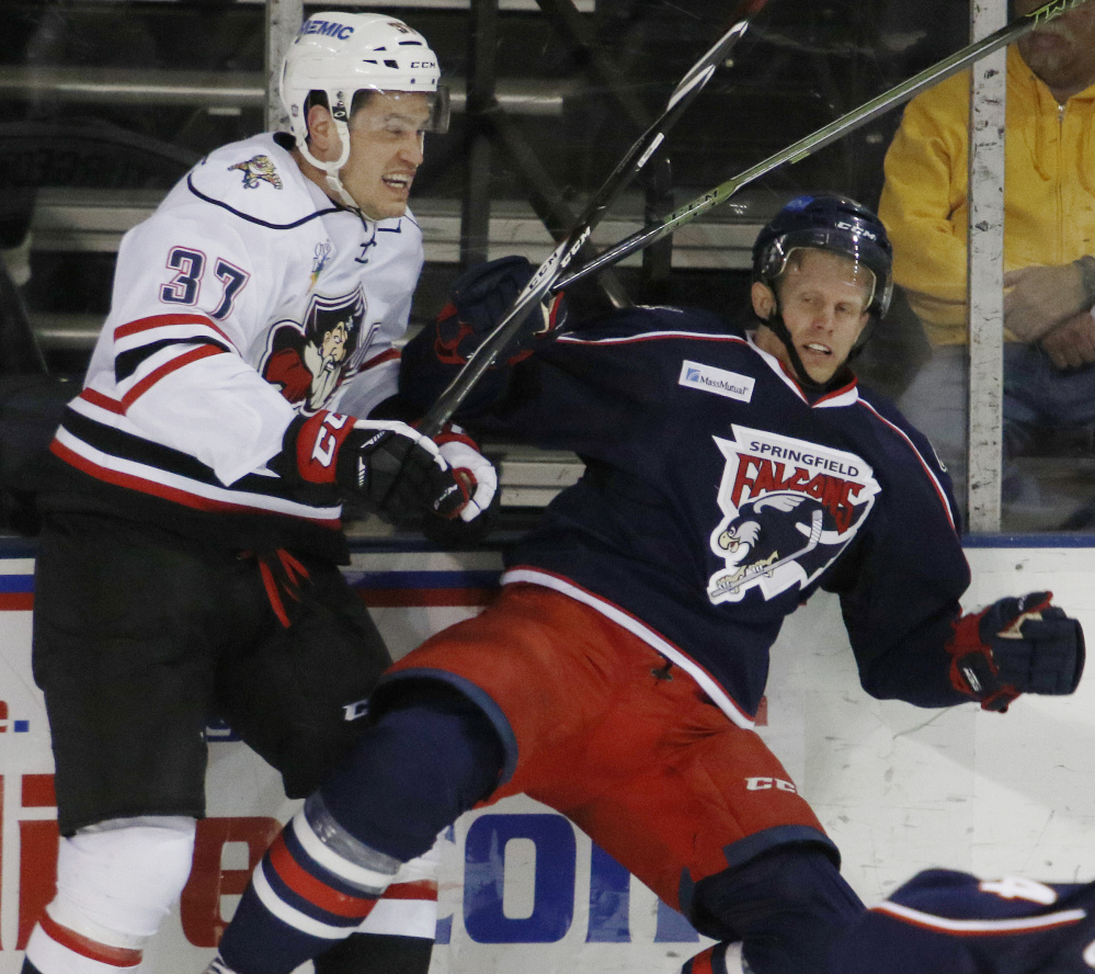 Tony Turgeon of the Portland Pirates, left, checks Philip Samuelsson of the Springfield Falcons into the boards Wednesday night during the second period of Portland’s 5-2 victory at the Cross Insurance Arena.