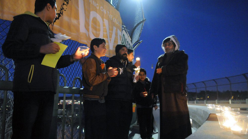 Members of a variety of faiths gather Wednesday to light candles and stand together in a show of support on Memorial Bridge in Augusta.