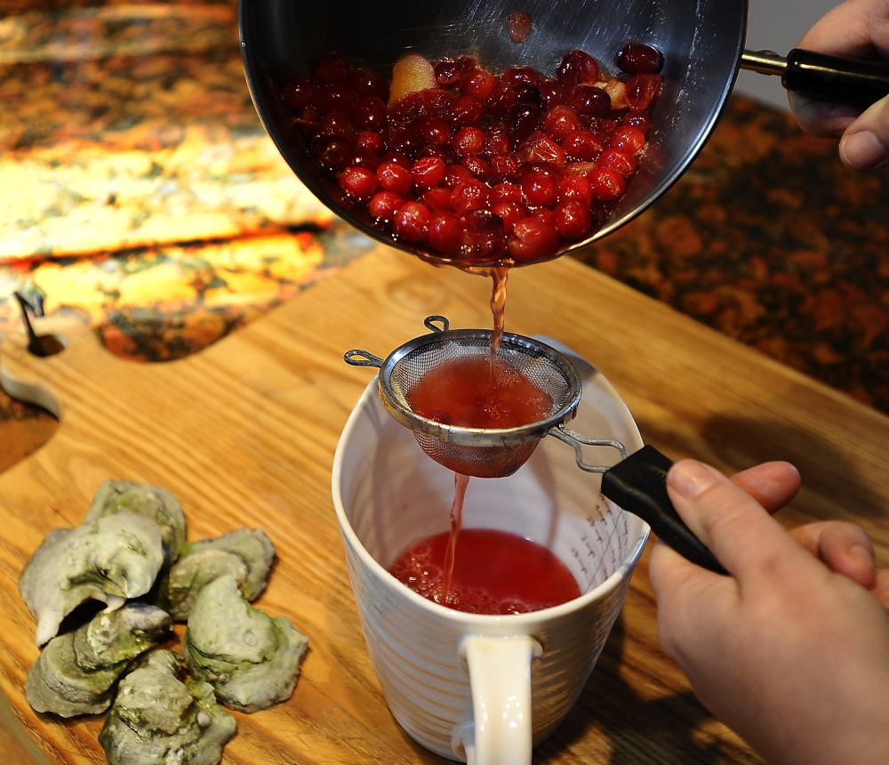 Christine Burns Rudalevige strains liquid from the cranberry, shallot and wine vinegar mixture to make mignonette for Maine oysters on the half shell.
Gordon Chibroski/Staff Photographer