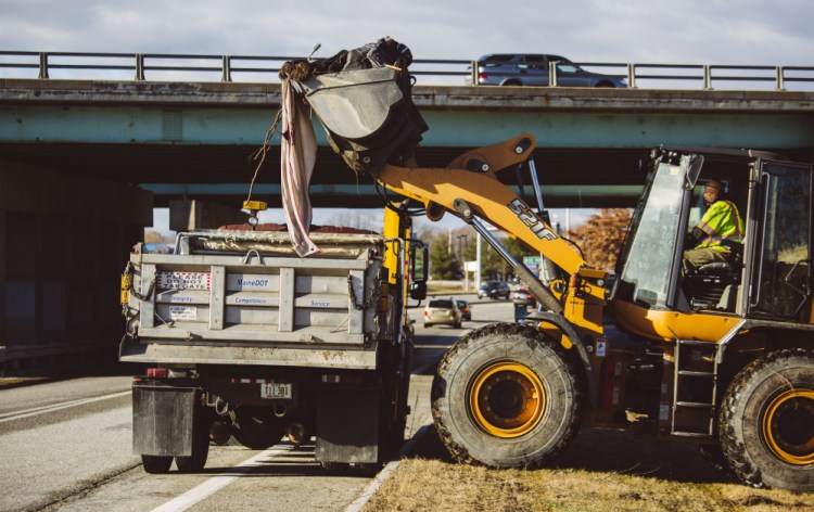 State workers remove the belongings of at least one homeless person who was living in a camp near the Exit 5 off-ramp on Interstate 295. One-and-a-half truckloads of materials were removed in all.