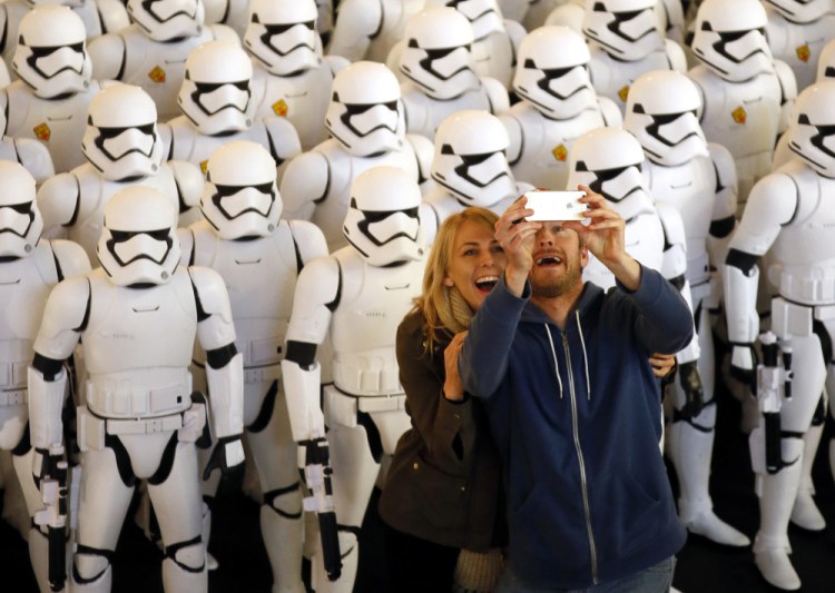 A couple takes a selfie together in front of over 100 JAKKS BIG-FIGS Stormtrooper action figures as part of an installation at The Americana at Brand for the opening of Star Wars: The Force Awakens in Glendale, Calif.