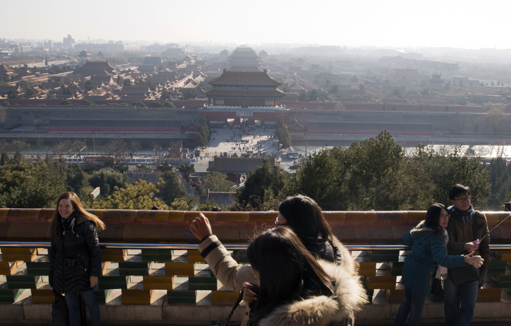 Visitors take photos from a pavilion overlooking the Forbidden City in Beijing on Friday. A wave of smog is predicted to settle over the city from Saturday to Tuesday.