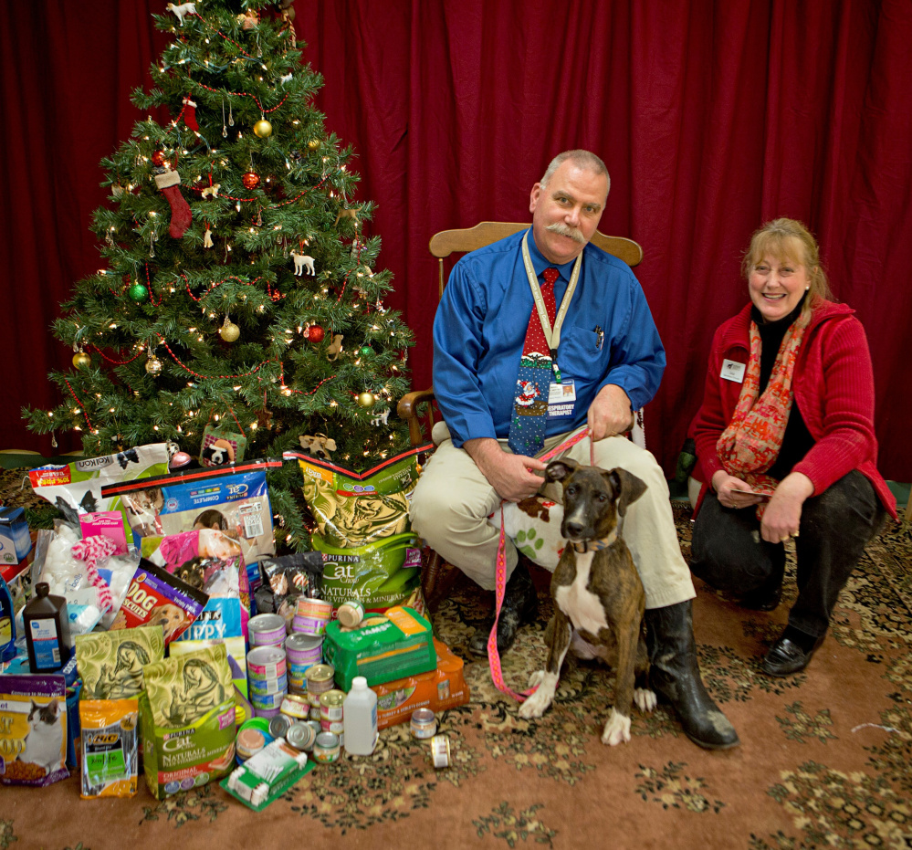 Howard Mette, a department director at Inland Hospital, poses in front of the gifts donated by hospital workers to the Humane Society Waterville Area animal shelter. With Mette are Paisley, a shelter resident, and the shelter’s director, Lisa Smith.