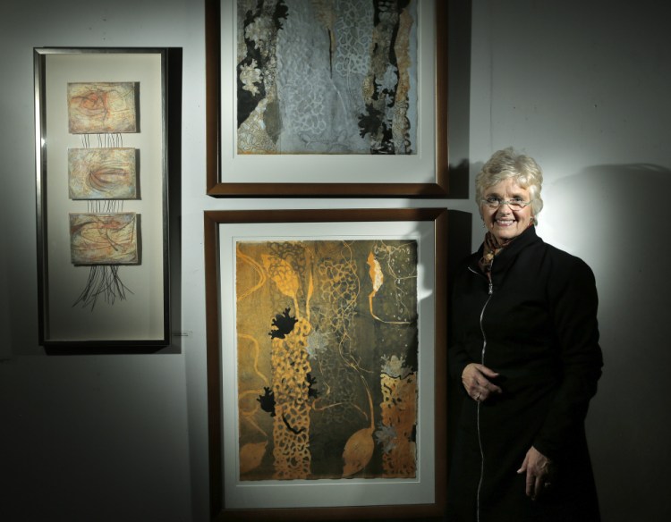 Kate Chappell at her Westbrook studio with recent works. The two at center are collagraph monoprints titled “Earth Matrix I” (bottom) and “Earth Matrix II.” At left is a mixed-media piece called “Flute of Interior Time.”