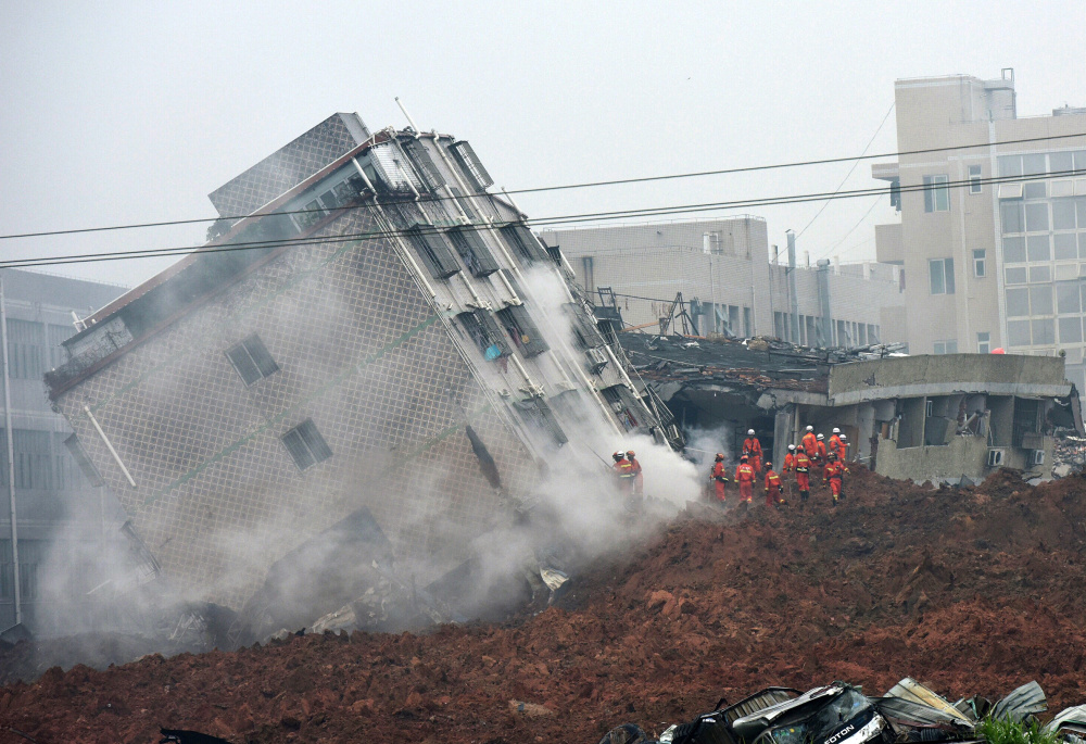 Rescuers cluster near a collapsed building as they search for survivors Sunday after a landslide in Shenzhen, a city in south China’s Guangdong province.