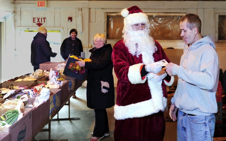 Secret Santa gives $100 bills to people at the Food Pantry in Alfred, including volunteer Anthony Cole of Kennebunk, right.