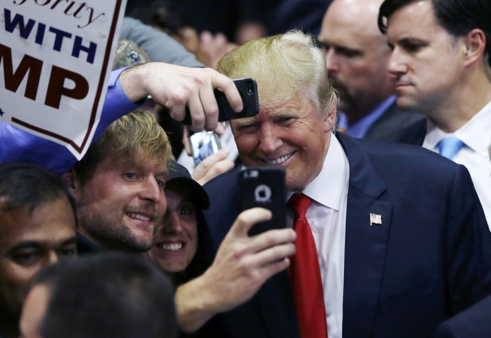 Republican presidential candidate Donald Trump poses with supporters after a rally Monday in Grand Rapids, Mich. Analysts say his higher numbers in online polling may be a result of more educated voters picking him in that more “anonymous environment.”