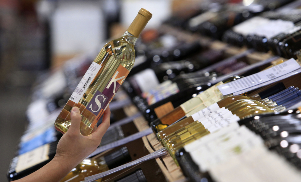 A shopper holds up a bottle of wine from a large selection at a Costco warehouse store Tuesday, Aug. 24, 2010, in Seattle. The cavernous stores in Costco's home state lack something you can find in its warehouses in California, Alaska and dozens of other states: jumbo-sized bottle of Maker's Mark, Absolut vodka and other popular brands of hard liquor. Two ballot measures on the November ballot would largely sweep away the state's post-Prohibition restrictions on alcohol, and perhaps herald a broader push to bring booze into the big box stores in the roughly 20 states that still keep a tight lid on the hard stuff. (AP Photo/Elaine Thompson)