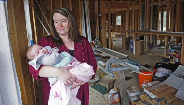 Missy Peasley holds daughter Brooke as she talks about her family’s new home that’s under construction in Somerville.