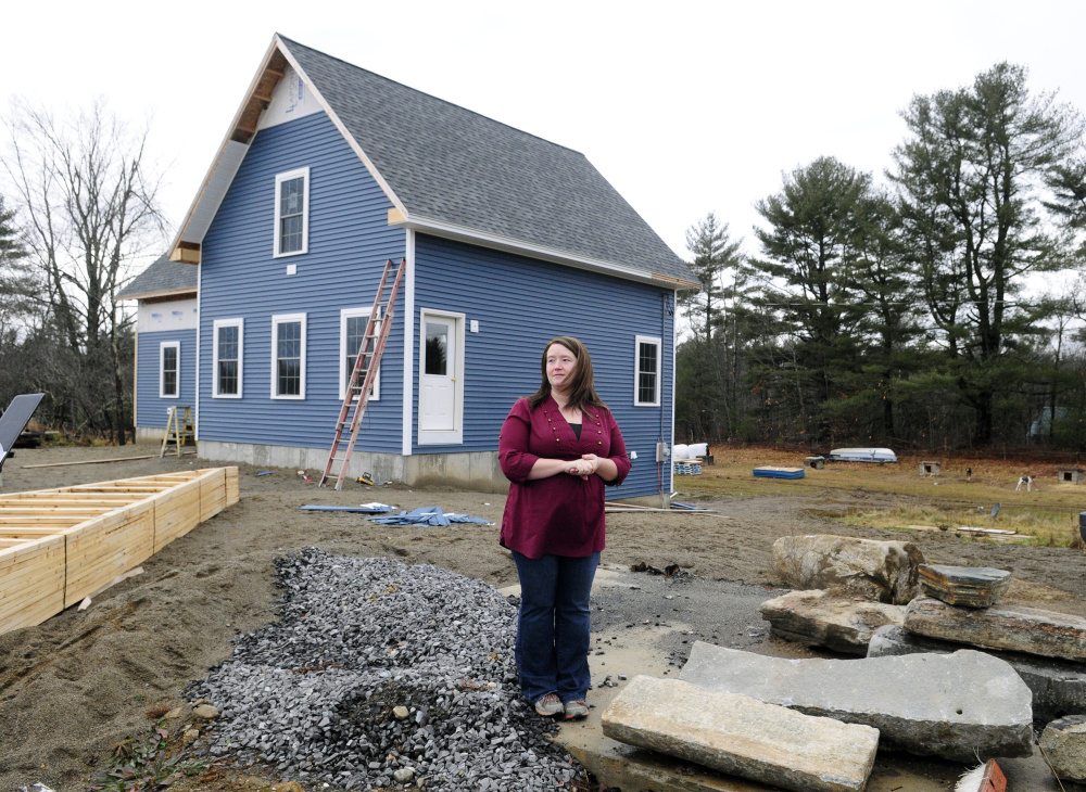 Missy Peasley stands on the site of her family’s home that burned down and in front of her family’s new home on Dec. 18 in Somerville.