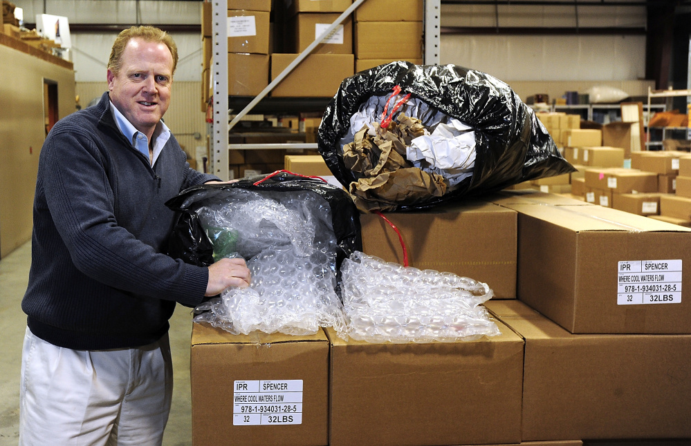 Dean Lunt, owner of Islandport Press, shows the bags of recycled packaging from Gulf of Maine Books that they will use in packing their books for shipping.  Gordon Chibroski/Staff Photographer