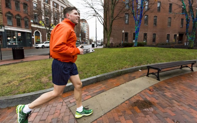 John Marshall, a holiday visitor from Salem, New Hampshire, jogs in a pair of shorts on Dec. 24 past the holiday lights on Exchange Street in Portland. 