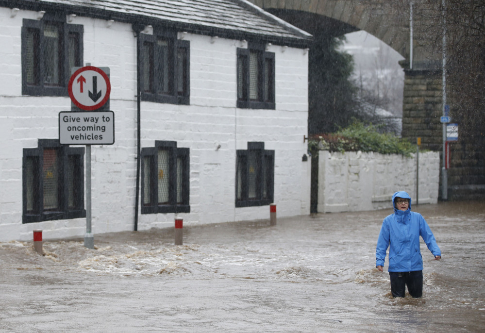 A person wades through flood water at Mytholmroyd in Calderdale, West Yorkshire, on Saturday. Parts of northwest England already hit hard by flooding in recent weeks were under severe flood warnings Saturday because of forecasts for more heavy rain, with some areas being evacuated.