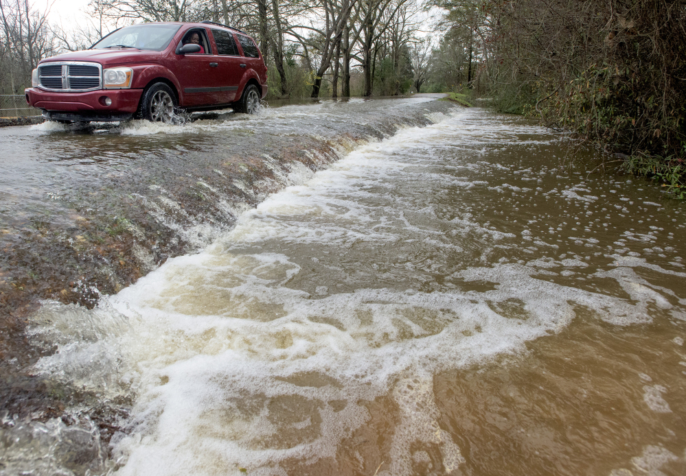 A vehicle drives along a flooded road in west Montgomery, Ala., on Christmas morning. 