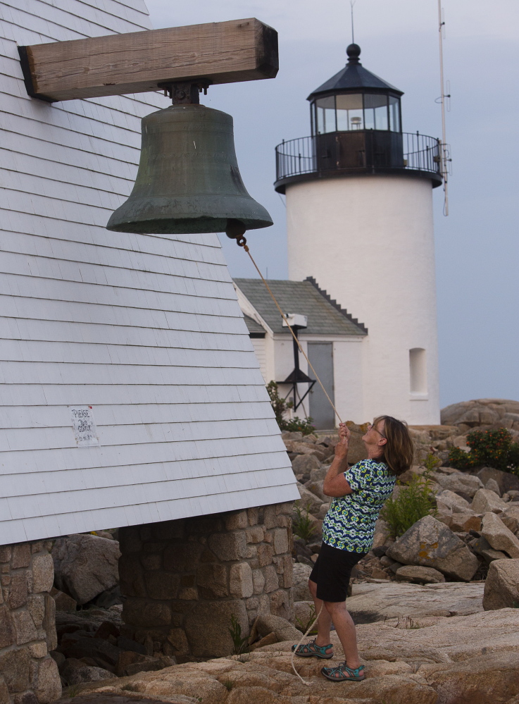 Lee Maynard, a Kennebunkport Conservation Trust volunteer, rings the ceremonial bell at sunset after doing work to maintain one of the trust’s properties. The trust has protected 2,400 acres and 15 miles of a forest trail over 40 years.