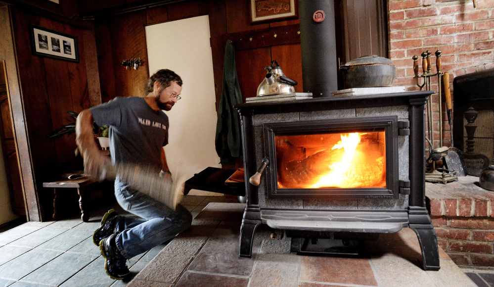 Steve Fuller of Peru feeds his new Equinox wood stove. He and his wife, Marcia, are among the first Mainers to receive $1,000 for replacing an older burner with one certified by the EPA.