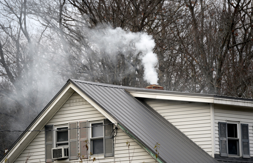 Smoke wafts from a chimney at a home in Livermore, one of 10 Androscoggin River valley communities where homeowners are eligible for a wood stove change-out program that provides a $1,000 voucher for replacing older burners with stoves that are approved by the Environmental Protection Agency. Shawn Patrick Ouellette/Staff Photographer