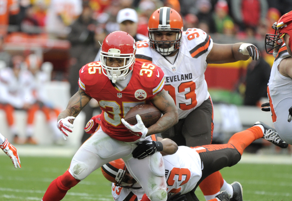 Chiefs running back Charcandrick West runs away from Cleveland’s John Hughes, bottom, and Craig Robertson as Kansas City clinched a playoff spot with a 17-13 win Sunday.