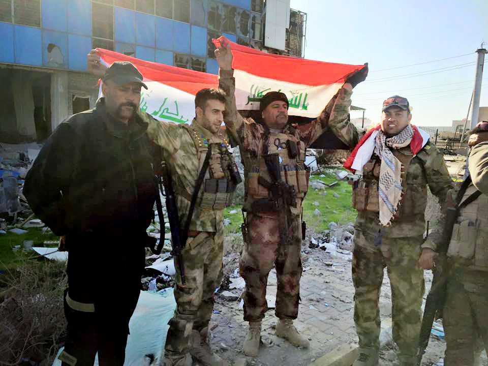 Iraqi soldiers hold national flags in the government complex in central Ramadi on Monday after retaking the strategic site from Islamic State militants who have occupied the city since May.