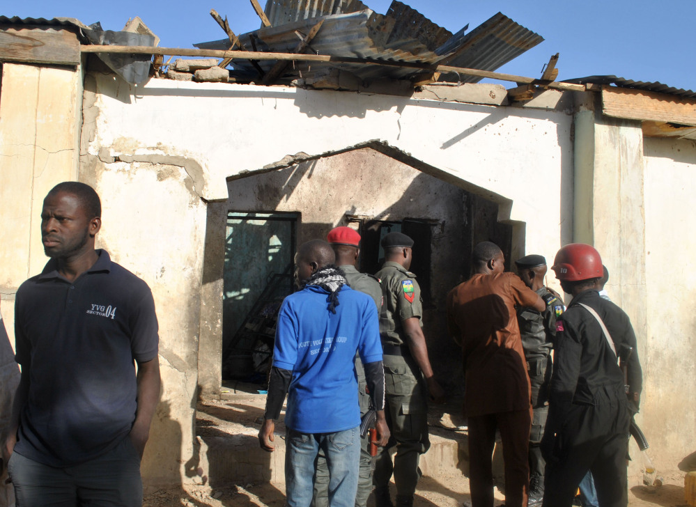 People gather at a damaged building following an attack by Boko Haram in Maiduguri, Nigeria, on Monday.
