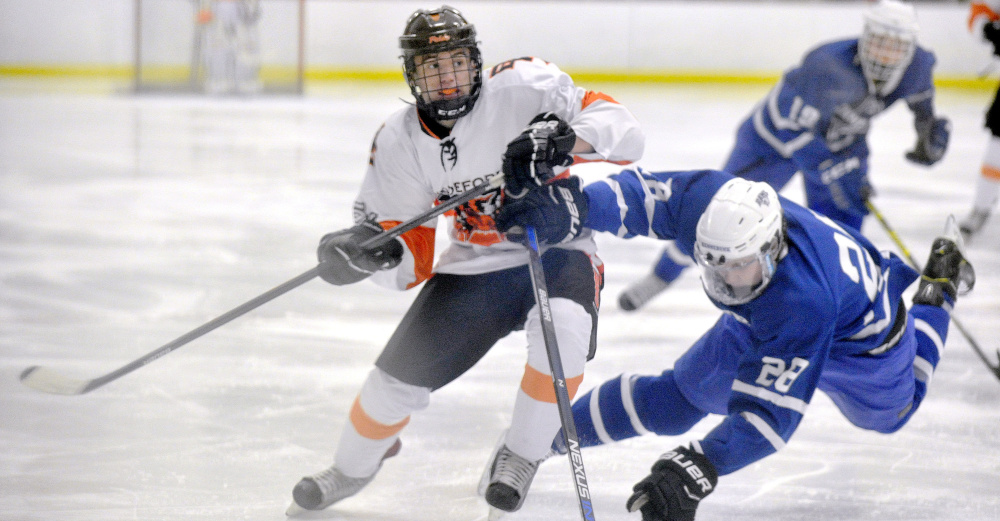 Max Mourmouras of Biddeford avoids a check from Nate Jewett of Kennebunk and sends the puck up the ice Monday during Biddeford’s 7-2 victory at Biddeford Ice Arena. The Tigers improved their record to 4-3 and droped Kennebunk to 3-4-1.