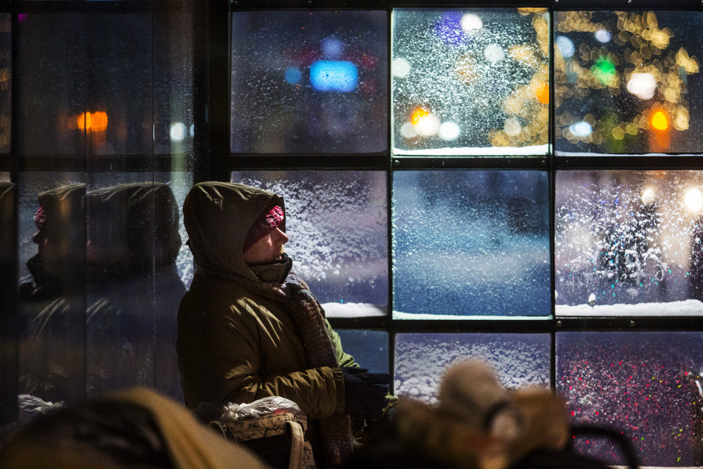 John Horvat, a homeless man in Portland, finds shelter at a Congress Street bus stop as the season’s first snowstorm hit southern Maine. More low temperatures and freezing drizzle are likely Wednesday.