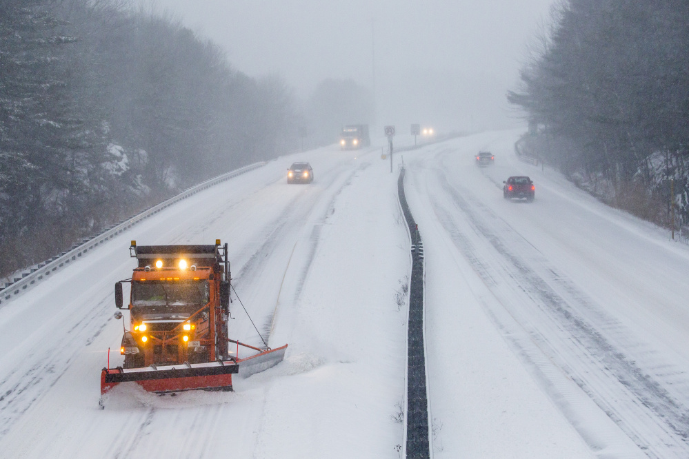 A plow truck clears the westbound lane of the Maine Turnpike spur in Falmouth as cars head into Portland during the morning commute in December 2015.