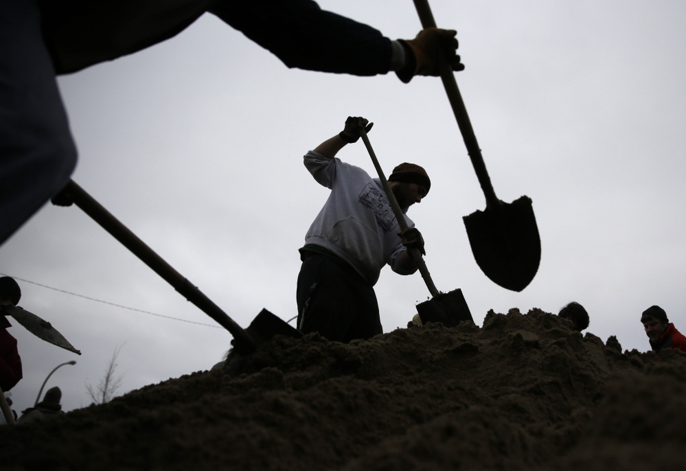 Volunteers use shovels atop a pile of sand as they help fill sandbags Tuesday in St. Louis.