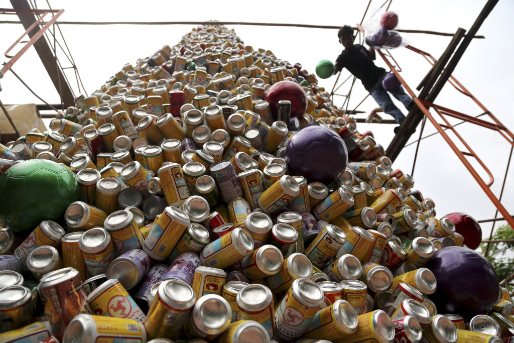 A worker arranges about 10,000 discarded beverage cans to form a Christmas tree in front of a church in Jakarta, Indonesia, Friday. Colored soccer balls are used as ornaments.