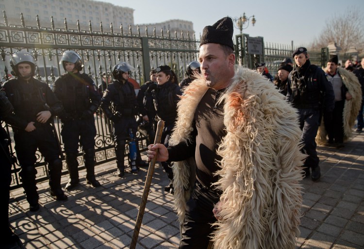 A shepherd whistles after breaking through riot police lines during a protest in Bucharest, Romania, on Tuesday. More than 1,000 angry shepherds broke through fences into the grounds of Romania’s Parliament, scuffled with riot police who fired tear gas, to protest a law that regulates the number of sheepdogs they can use and bans them from grazing sheep during the winter.