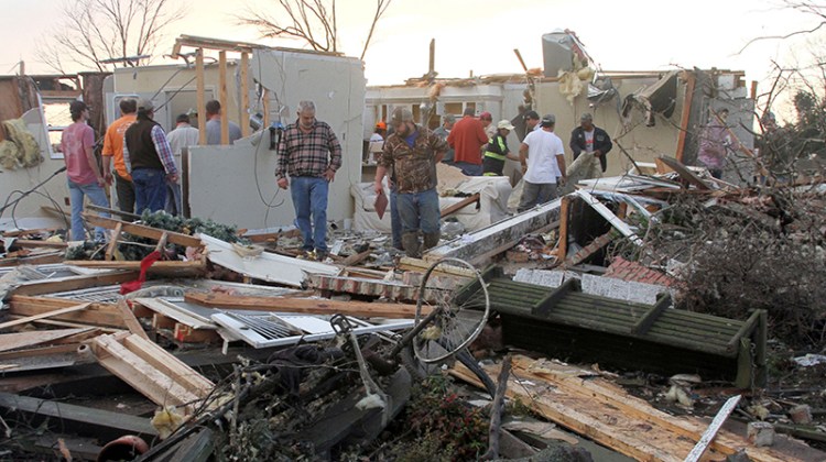 People inspect a storm-damaged house in Roundaway, Mississippi.