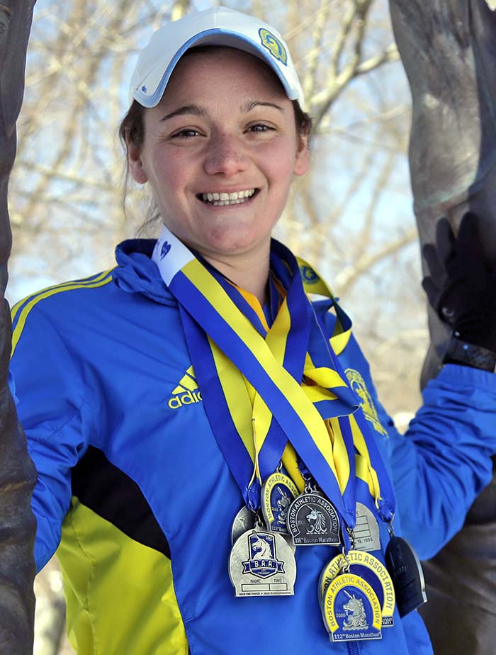 Becca Pizzi wears some of her medals from the 15 Boston Marathons she has completed. The Associated Press