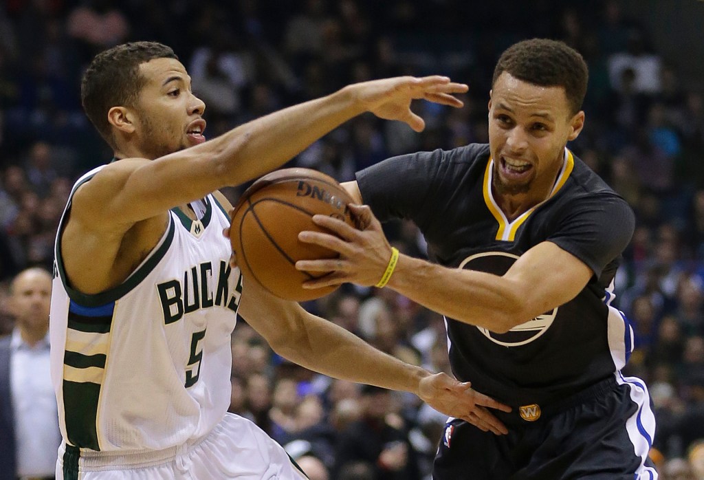 Stephen Curry, right, of the Golden State Warriors looks to drive against Michael Carter-Williams of the Milwaukee Bucks in the first half of Milwaukee’s 108-95 victory Saturday night that sent Golden State to its first loss. The Associated Press